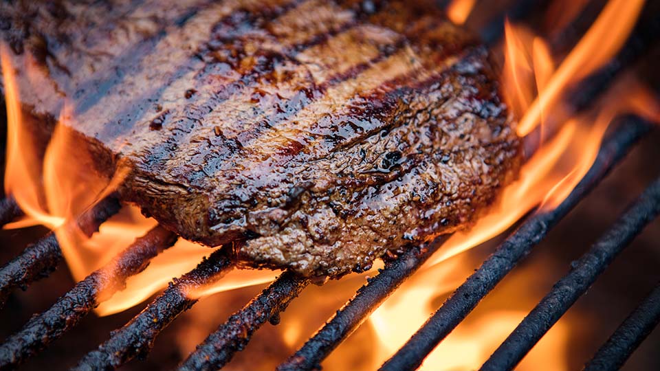 steak cooking on a flaming grill